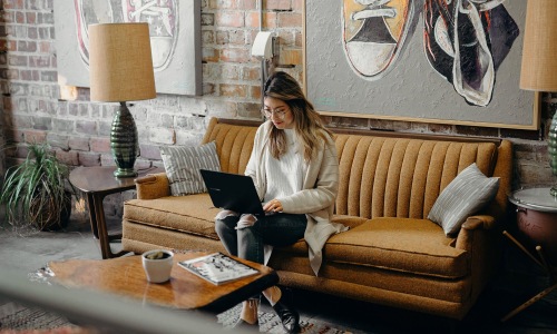 a woman sitting on a couch working on a laptop
